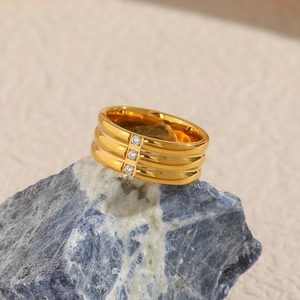 Detailed shot of a triple-layered gold ring with three inset zircons on a dark blue stone
