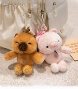 Detail of plush capybara and pig keychains with Fashion tags hanging on a beige backpack