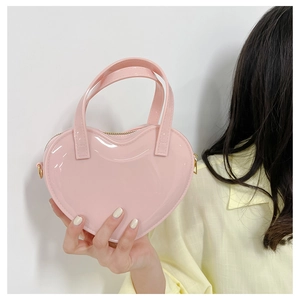 Detail of pink heart-shaped patent leather handbag with dual handles and metal zipper