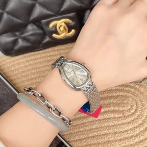 Detailed view of silver steel watch with oval dial and Roman numerals on a model wrist