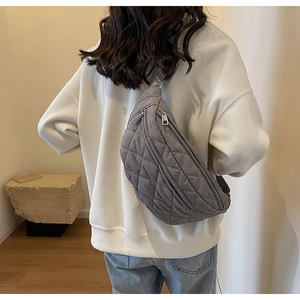 Detailed macro view of a grey quilted crossbody chest bag worn by a model