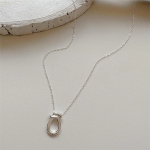 Close-up of minimalist 925 sterling silver knotted pendant on textured stone background