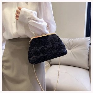 Detail of elegant black clutch featuring 3D fabric roses and a gold chain strap
