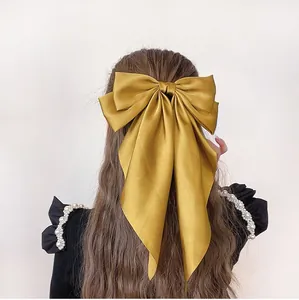 Close-up of oversized ginger satin bow hair clip with long ribbons on wavy hair