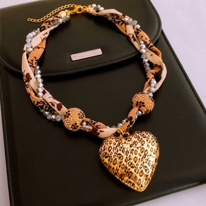 Macro view of leopard print heart pendant on beaded necklace over black leather background