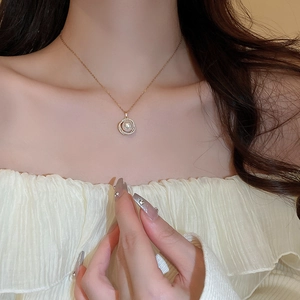 Détail d'un collier avec pendentif en perle plaqué or et zircons sur le cou d'un modèle