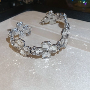 Detailed view of silver open cuff bracelet with sparkling clear floral-shaped gemstones