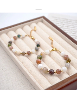 Detail of beaded gemstone bracelets with gold lobster clasps in a beige velvet jewelry box