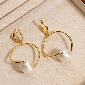 Detailed macro view of gold plated metal hoop earrings with elegant white large pearls