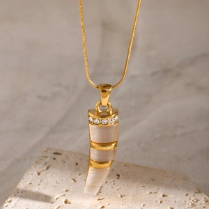 Detailed close-up of 18k gold-plated horn pendant with ivory cat eye stone on stone base