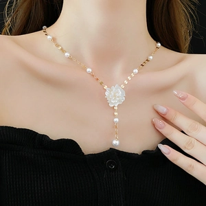Detail of Y-shaped gold flower necklace with pearls worn on model neckline