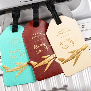 Close-up of three faux leather travel luggage tags in turquoise, burgundy, and beige