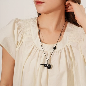 Close-up of a Zen-style necklace featuring a black gourd pendant and ceramic beads