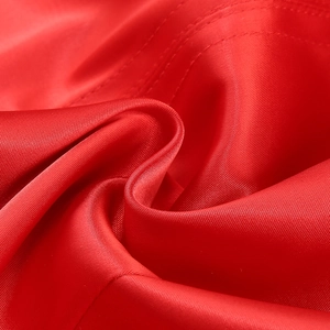 Macro shot of smooth red satin fabric showing luxurious glossy texture and flowing drapes