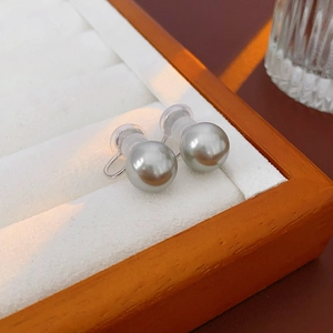 Detailed close-up of grey pearl ear clips with silicone pads in a white display tray