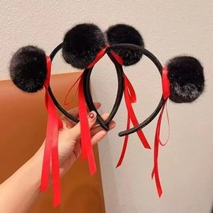 Detail shot of cute black plush pom-pom headbands with red ribbons in hand-held view