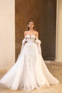 Dettaglio dell'abito da sposa a corsetto bianco con ricami in pizzo e maniche a sbuffo