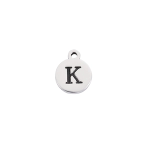 Macro shot of silver stainless steel round pendant with engraved black letter K detail