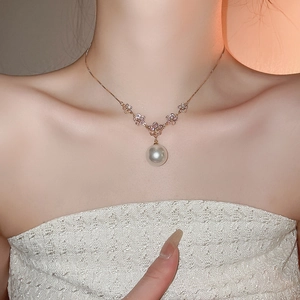 Detail of zircon flower and pearl choker necklace on a model wearing white lace