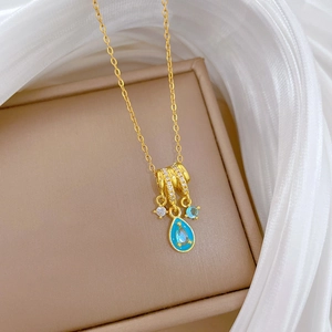 Luxurious gold titanium necklace with turquoise teardrop pendant on a beige jewelry box