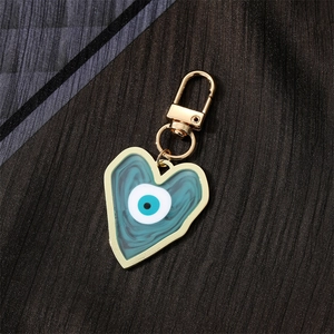 Detail of a heart-shaped evil eye keychain with blue enamel and gold-tone alloy hardware