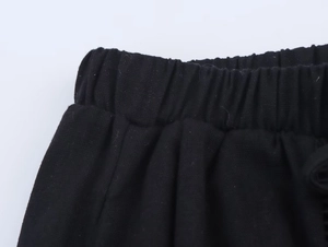 Detail of black linen pants featuring an elastic waistband with knit fabric texture