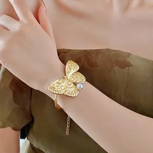 Elegant gold butterfly cuff bracelet with pearl accent and vintage carved texture details