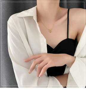 Close-up of a hollow heart pendant necklace in gold finish worn on the collarbone