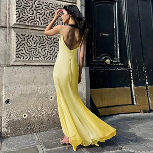 Détail d'une élégante robe longue dos nu en satin et mousseline jaune portée par un mannequin