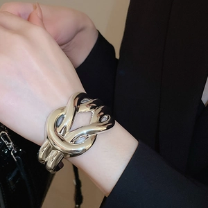 Detailed view of bold chunky gold knotted cuff bracelet with polished metallic finish