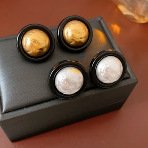 Detail of round vintage earrings featuring hammered metal spheres in matte black frames
