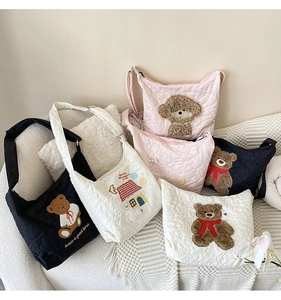 Quilted tote bags with plush bear and puppy embroidery on a soft fabric surface