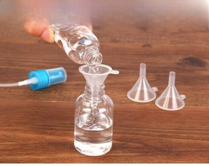 Macro view of pouring liquid into a mini PP funnel and spray bottle for travel use