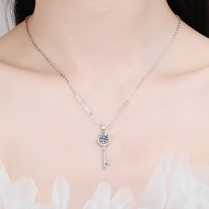 Close-up of elegant key-shaped necklace with shimmering crystals on model's neckline