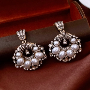 Close-up of vintage gold pearl earrings with crystals on dark velvet display background