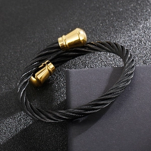 Detailed view of black cable twist bracelet with gold metal end caps on dark background