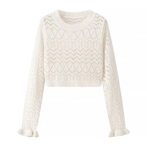 Detail of white crochet knit top featuring openwork floral pattern and ruffle cuffs
