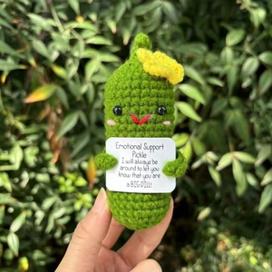 Close-up of hand-knitted emotional support pickle with positive message card