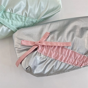 Detail of quilted metallic bow pencil case featuring smooth silver and pink textures