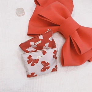 Detail of red and white canvas cosmetic bags with bow prints and brand label