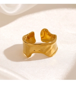 Detailed view of a gold irregular textured adjustable ring on white silk fabric