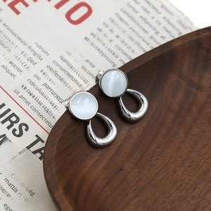Elegant silver geometric cat eye stone stud earrings on a vintage wooden tray