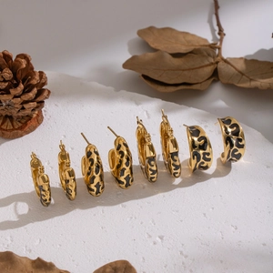 Golden leopard print hoop earrings in four sizes displayed on a marble stone surface