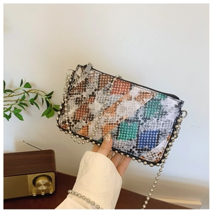 Close-up of multicolor snakeskin patchwork envelope bag with silver ball chain strap