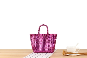 Gros plan d'un sac cabas tissé violet métallisé sur une table en bois avec décor
