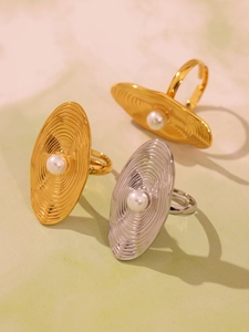 Close-up of gold and silver geometric ripple rings with white pearl inlay on marble