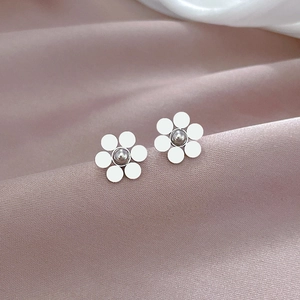 Macro shot of silver titanium steel six-petal flower studs on soft silk fabric