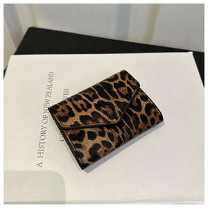 Detail of leopard print faux leather envelope wallet with textured finish on a white book