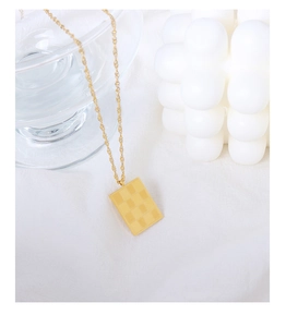 Detail of a vintage gold checkered rectangular pendant on a fine water wave chain