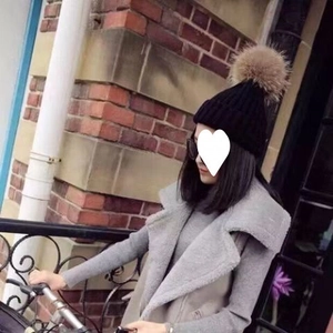 Detail of a black knit beanie with a fluffy brown faux fur pom pom for winter warmth